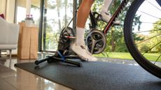 rider cycling indoors on a Wahoo trainer, wearing white indoor cycling shoes with white socks